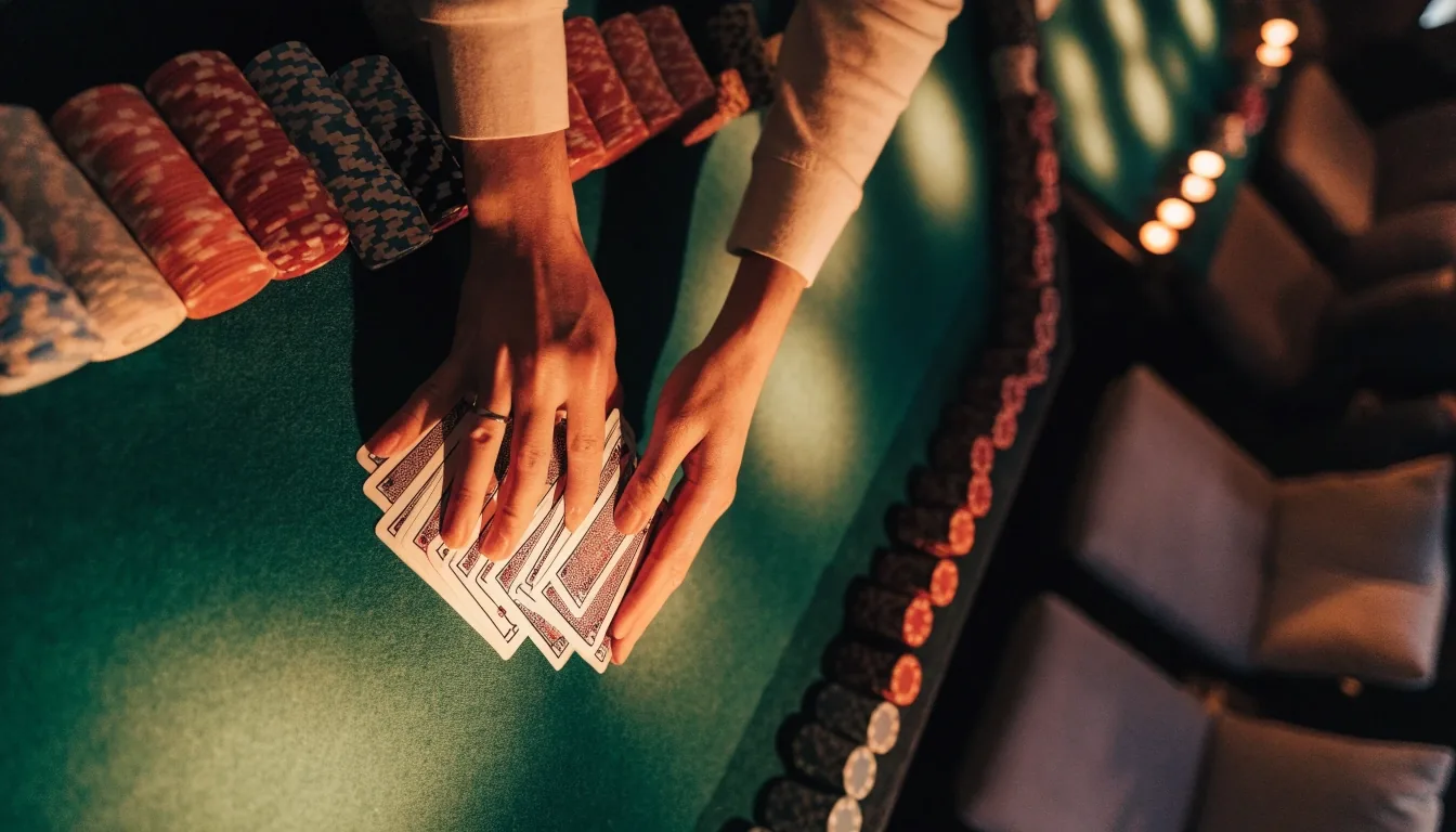 Stół pokerowy z żetonami i rękami krupiera podczas rozdania kart